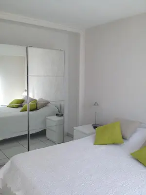 a white bedroom with a bed and a mirror at Appartement vacances cannes in Cannes