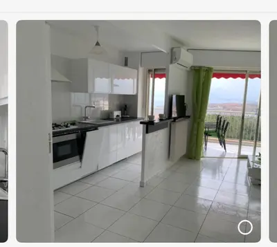 a kitchen with white cabinets and a large window at Appartement vacances cannes in Cannes