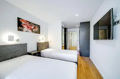 two beds in a bedroom with white walls at Appartements Croisette Grand Hôtel in Cannes