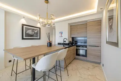 a kitchen with a wooden table and white chairs at Appartements Croisette Grand Hôtel in Cannes