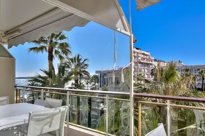 a balcony with a view of the ocean and palm trees at Appartements Croisette Grand Hôtel in Cannes