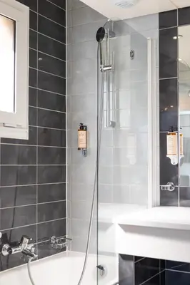 a bathroom with a shower and a sink and a tub at Cézanne Hôtel in Cannes