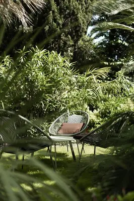 a chair sitting in the grass near some bushes at Cézanne Hôtel in Cannes