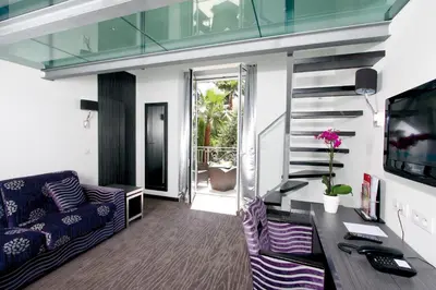 a living room with a couch and a staircase at GOLDEN TULIP CANNES HOTEL de PARIS in Cannes