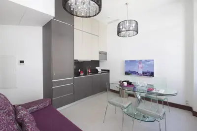 a living room with a glass table and a kitchen at GOLDEN TULIP CANNES HOTEL de PARIS in Cannes