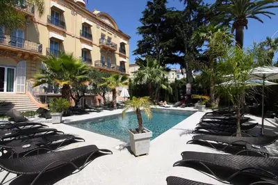 a swimming pool with lounge chairs and a building at GOLDEN TULIP CANNES HOTEL de PARIS in Cannes