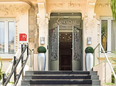 a man and a woman sitting at a table in front of a window at Hotel Renoir in Cannes