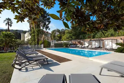 a swimming pool with lounge chairs next to a building at Hôtel Château de la Tour Cannes in Cannes