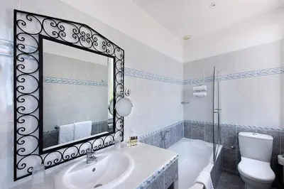 a bathroom with a mirror and a sink and a toilet at Hôtel Château de la Tour Cannes in Cannes
