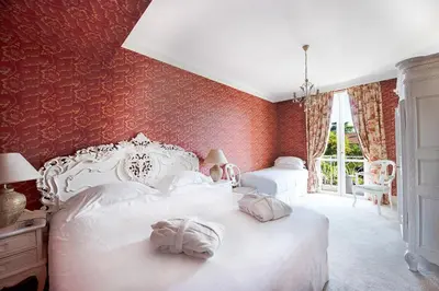 a bedroom with two white beds with red walls at Hôtel Château de la Tour Cannes in Cannes