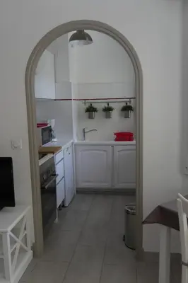 an archway in a kitchen with white cabinets and a sink at Studio Terrasse in Cannes