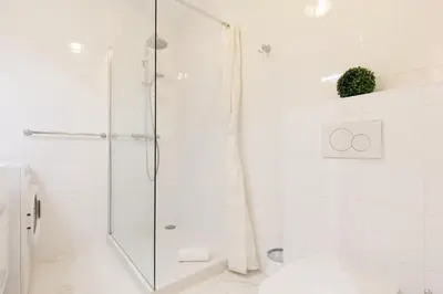 a white bathroom with a shower and a toilet at Le Minerve YourHostHelper in Cannes