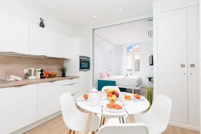 a white kitchen with a table with fruit on it at L'Albion YourHostHelper in Cannes