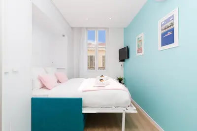 a bedroom with a white bed with pink pillows at L'Albion YourHostHelper in Cannes