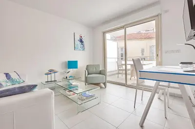 a white living room with a blue table and chairs at Appartement Résidence Montaigne in Cannes