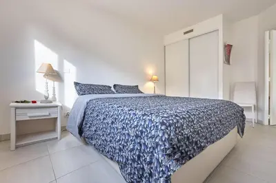 a white bedroom with a blue comforter on a bed at Appartement Résidence Montaigne in Cannes