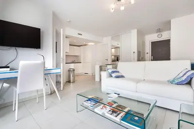 a living room with a white couch and a glass table at Appartement Résidence Montaigne in Cannes