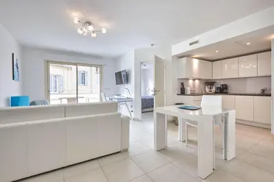 a kitchen with white cabinets and a white table at Appartement Résidence Montaigne in Cannes