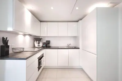 a white kitchen with white cabinets and a sink at Appartement Résidence Montaigne in Cannes