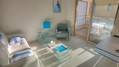 a living room with a glass table and a chair at Appartement Résidence Montaigne in Cannes