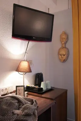 a flat screen tv on a wall above a desk with a lamp at ATH hôtel Athénée in Cannes