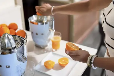a woman is juicing an orange in a juicer at Best Western Hôtel des Orangers Cannes in Cannes