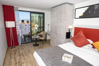 a hotel room with a bed and a balcony with people at Eden Hotel & Spa in Cannes