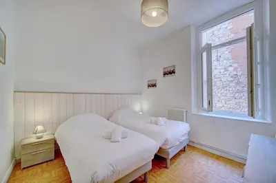 two beds in a room with a window at IMMOGROOM - Suquet - 2 min from the beaches in Cannes