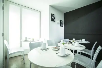a dining room with white tables and white chairs at Hotel Schtak in Cannes