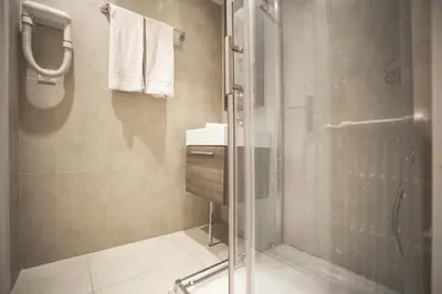 a bathroom with a glass shower and a sink at Hotel Schtak in Cannes