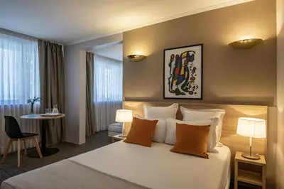 a hotel room with a large bed and a table at Le Cetai Cannes Beach Hotel in Cannes