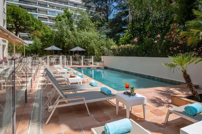 a pool with chaise lounge chairs and a row ofvisorvisor at Le Cetai Cannes Beach Hotel in Cannes