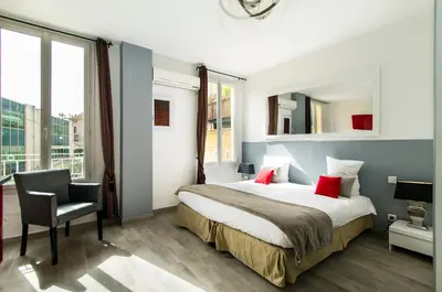 a hotel room with a bed and a chair at Florella République Apartment in Cannes