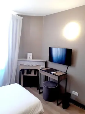 a bedroom with a bed and a desk with a television at Hôtel La Villa Tosca in Cannes