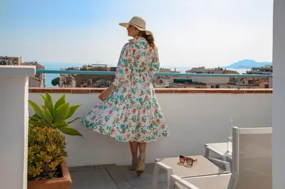 a woman in a floral dress standing on a balcony at BW Premier Collection Mondial in Cannes