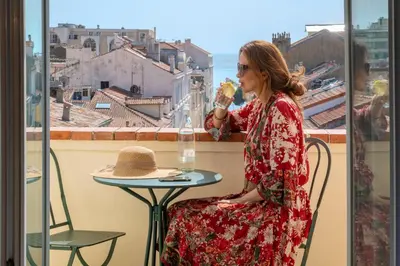 a woman sitting at a table eating food in front of a window at BW Premier Collection Mondial in Cannes