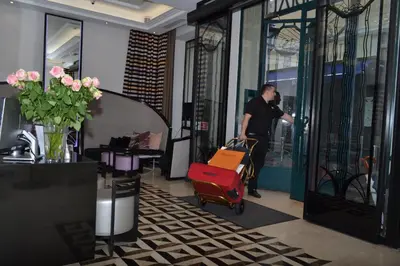a man pushing a luggage cart in a lobby at BW Premier Collection Mondial in Cannes