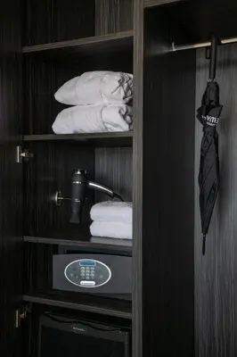 a closet with a shelf with towels and a tie at BW Premier Collection Mondial in Cannes