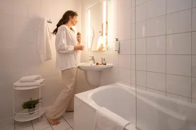 a woman standing in a bathroom with a sink and a tub at L'Esterel in Cannes