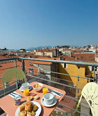 a table with food on a balcony with a view at L'Esterel in Cannes
