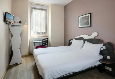 a bedroom with a white bed and a desk at L'Esterel in Cannes