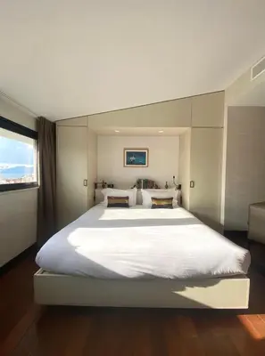 a large white bed in a bedroom with a window at Hôtel Cannes Centre Univers in Cannes