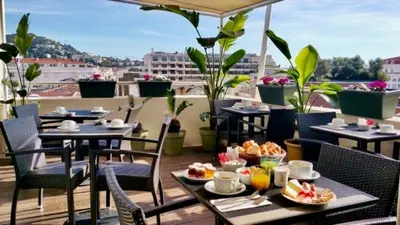 a table with plates of food on a balcony at Hôtel Cannes Centre Univers in Cannes