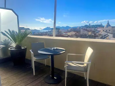 a table and two chairs on a balcony with a view at Hôtel Cannes Centre Univers in Cannes