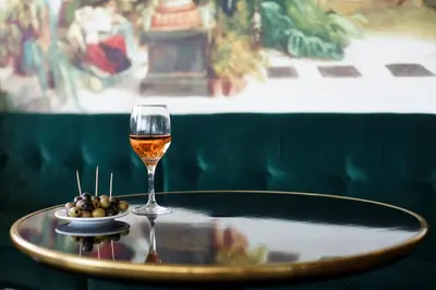 a glass of wine and a bowl of olives on a table at Hôtel Cannes Centre Univers in Cannes