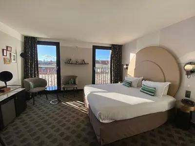 a hotel room with a bed and a desk and windows at Hôtel Cannes Centre Univers in Cannes