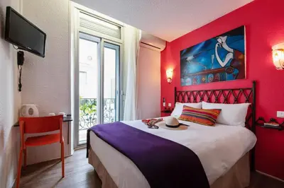 a red bedroom with a bed with a hat on it at Hôtel Brimer Cannes in Cannes