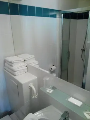 a bathroom with a toilet and a shower with towels at Hôtel Brimer Cannes in Cannes