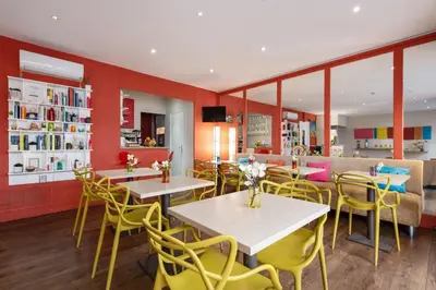 a restaurant with white tables and yellow chairs at Hôtel Brimer Cannes in Cannes