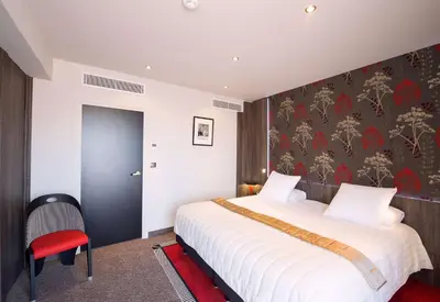 a bedroom with a large bed and a red chair at Best Western Premier Le Patio des Artistes Wellness Jacuzzi in Cannes
